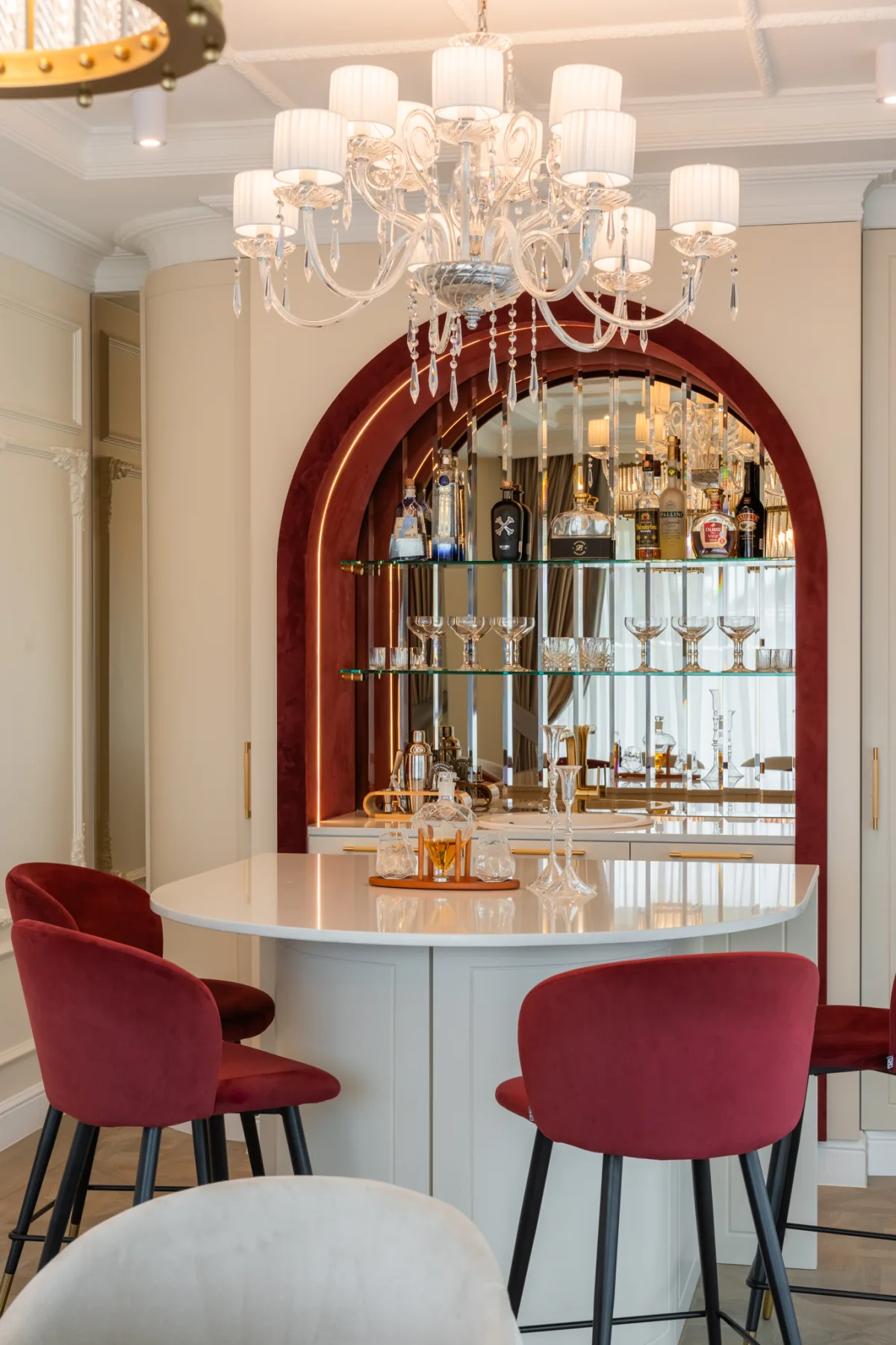 Dining room with a crystal chandelier, mirrored bar and burgundy chairs
