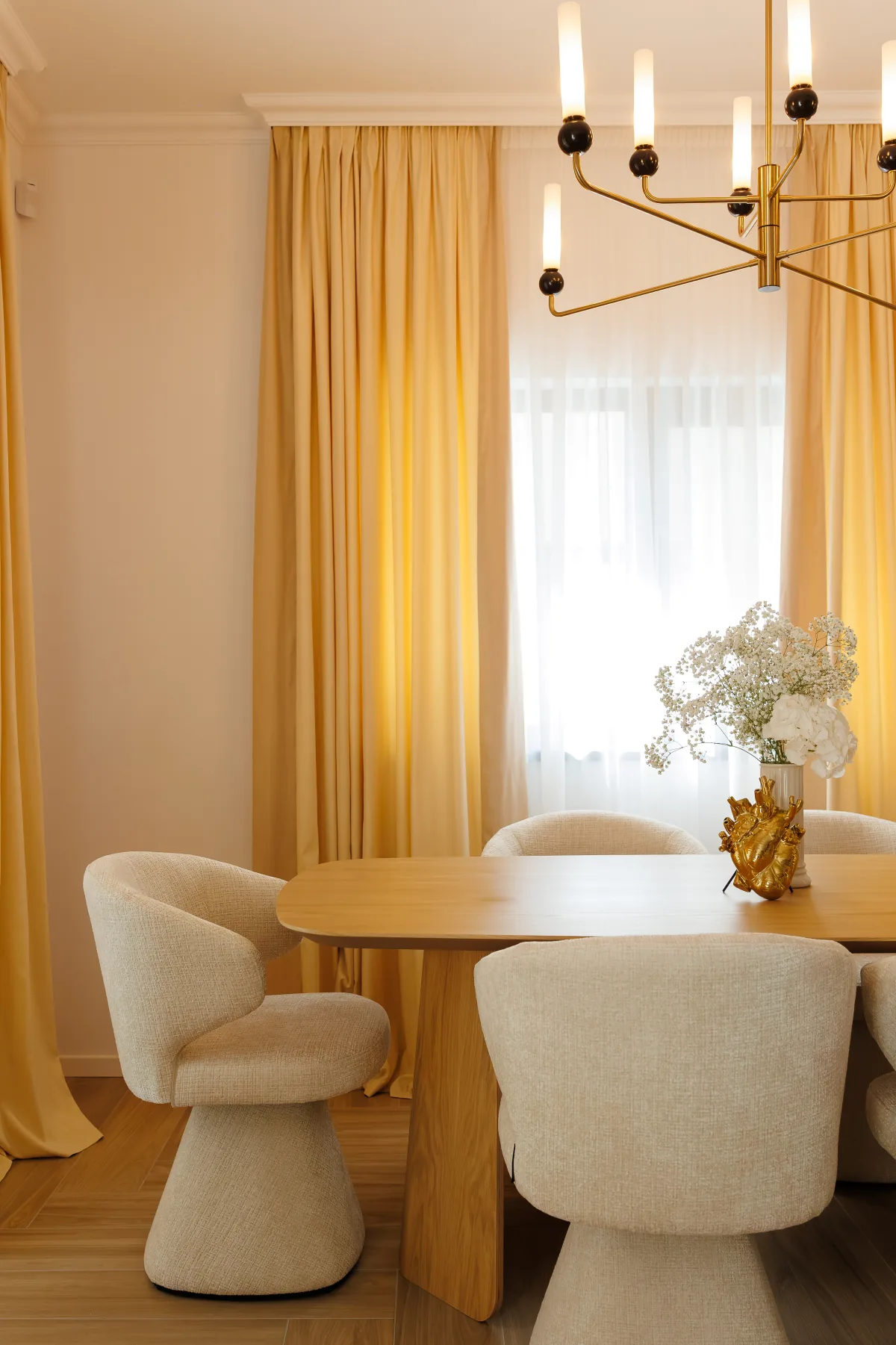 Dining room with golden curtains, a sculptural chandelier and warm wood finishes