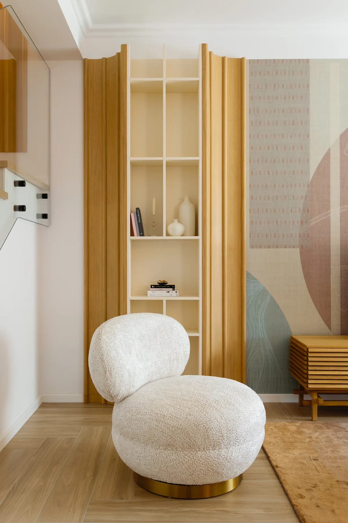 Sculptural bouclé chair beside oak shelving and a reading corner